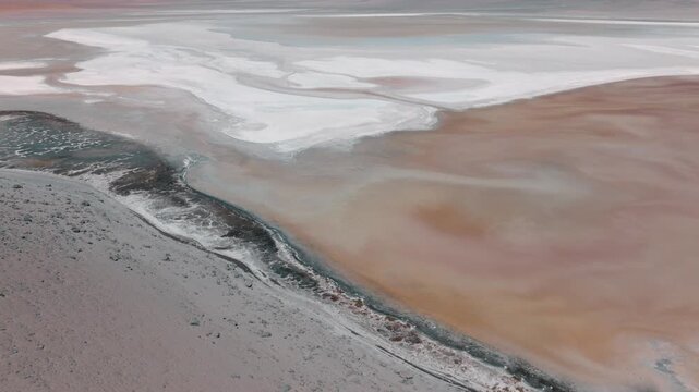 Aerial view of a salt lake in the Bolivian Altiplano, with pale mineral water and reflective surface. Minimalist landscape with soft tones and remote atmosphere.