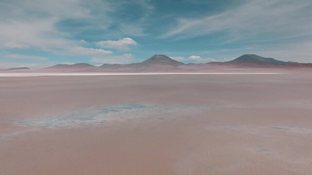 Aerial view of pink flamingos gathered on a high-altitude lagoon in Bolivia&rsquo;s Sud L&iacute;pez region, surrounded by volcanic landscapes and the Andes.