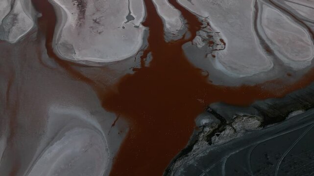 Aerial view of a salt lake in the Bolivian Altiplano, with pale mineral water and reflective surface. Minimalist landscape with soft tones and remote atmosphere.