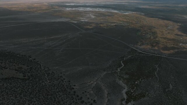 Aerial sunset over Sajama plains in Bolivia, warm golden light illuminating vast Altiplano landscape. Minimalist scenery with long shadows and dramatic sky.