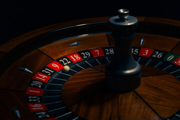 Stylish wooden roulette wheel with ball in winning pocket in a classic casino environment, illustrating gambling, risk and chance