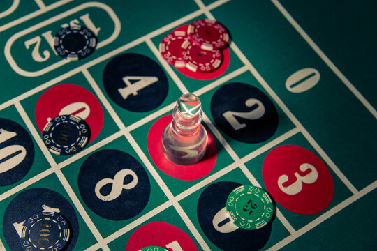 Poker chips and dolly on a roulette table in a casino setting, illustrating gambling, risk, chance and themes related to addiction and dangerous betting behavior