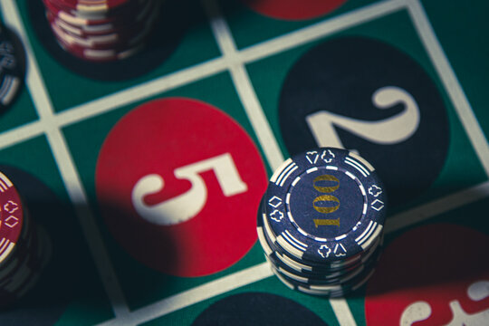 Poker chips on a roulette table in a casino setting, illustrating gambling, risk, chance and themes related to addiction and dangerous betting behavior