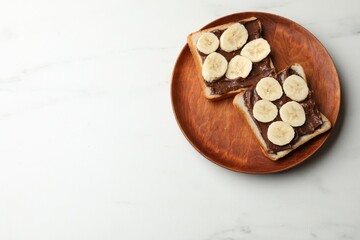 Obraz premium Toasts with chocolate paste and banana on white marble table, top view. Space for text