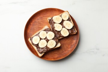 Obraz premium Toasts with chocolate paste and banana on white marble table, top view
