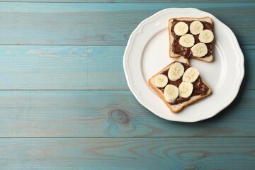 Plakat Toasts with chocolate paste and banana on light blue wooden table, top view. Space for text