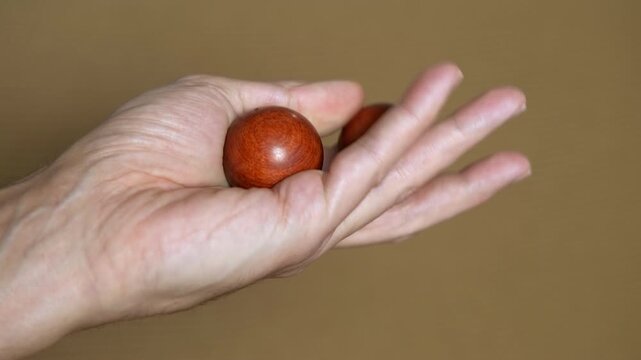 Person rotating chinese baoding balls in hand for health. Close-up of a person's hand rotating two wooden chinese health balls, a traditional exercise for stress relief, finger dexterity, meditation