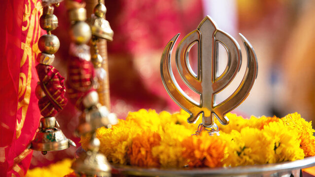 Golden khanda symbol with vibrant marigold flowers, Sikh celebration, festival decoration, cultural heritage, religious symbolism, traditional attire, festive atmosphere, yellow marigold garland