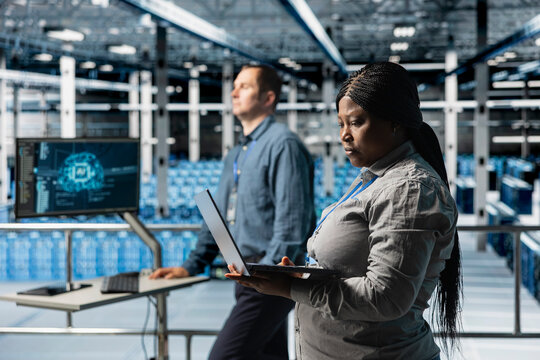 Teamworking data center technicians installing and upgrading hardware components. Server farm coworkers doing job tasks, implementing backup solutions to protect against data loss