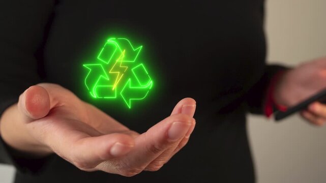 Businesswoman's hand holding a virtual icon of recycle sign and energy beam indoors