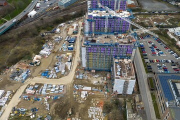 Naklejka premium Aerial drone close view of residential tower construction site in Leeds showing cranes scaffolding building materials and urban development in West Yorkshire England