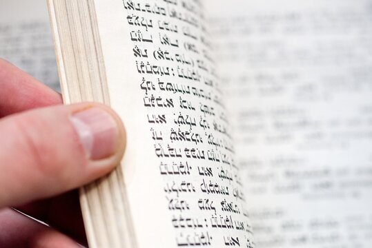 Hand Turning Page of Antique Hebrew Prayer Book