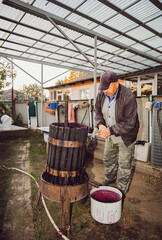 A senior man dismantles a wine press with a hammer.