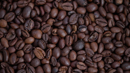 Obraz premium Closeup of glossy roasted coffee beans, Detailed macro image illustrating shiny dark roasted coffee beans with surface cracks and color differences suitable for branding