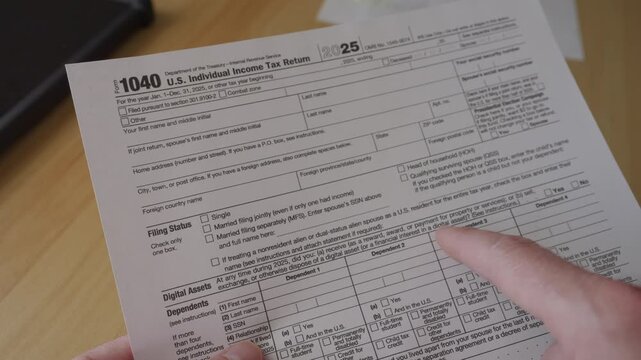 Man Filling In The Tax Form 1040. Person Calculates of Planning Budgets Yearly Personal Finance and Fills up US Tax Form 1040. Signing 1040 Income Tax Return. Names and numbers are fictitious.