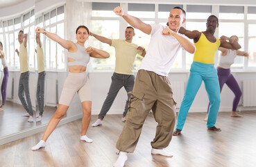 Fototapeta premium European man practices kicking and punching in process of self-defense. Multinational group activities, wrestling, maintaining physical fitness.