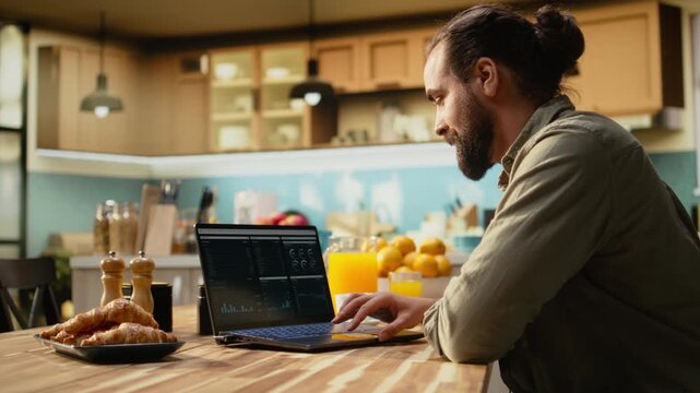 Remote worker using laptop and digital tools to analyze data and research information, seated in the kitchen. Telecommuting and outsourcing with charts and network connectivity, modern lifestyle.