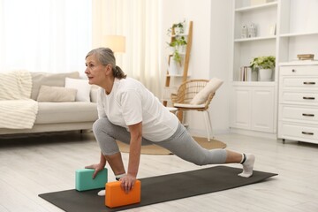 Senior woman exercising with yoga blocks at home. Fitness and sport