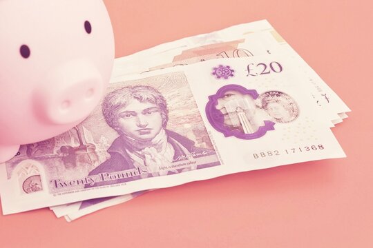  A pink piggy bank with a pound notes.