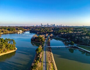 Fototapeta premium Aerial view of a lake and a dam road with a distant city skyline under blue sky