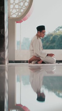 A Muslim man performing Islamic pray inside a mosque during Ramadan, a peaceful spiritual moment with beautiful mosque architecture and reflection on the polished floor.