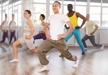 Obraz premium Group of multicultural men and women doing warm-ups before dance class in studio
