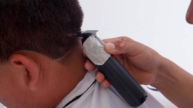 Professional barber creating modern hairstyle with electric clipper