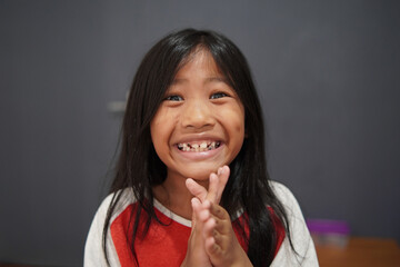 Fototapeta premium Cheerful little Asian girl clapping hands with a big smile, happy child celebrating success and feeling joyful, appreciation, achievement, and positive childhood emotion