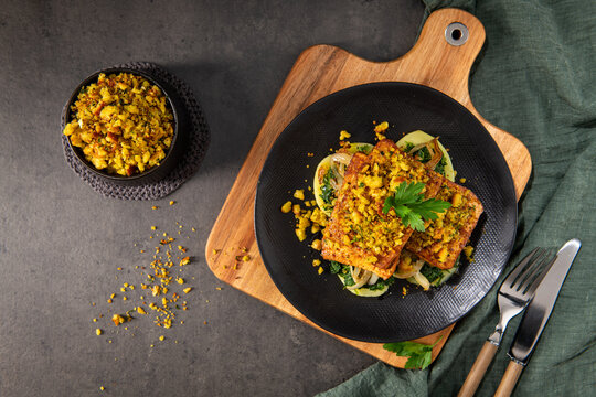 Top Down View of Roasted Tofu with Herb Crust and Saut&eacute;ed Greens on a Black Plate