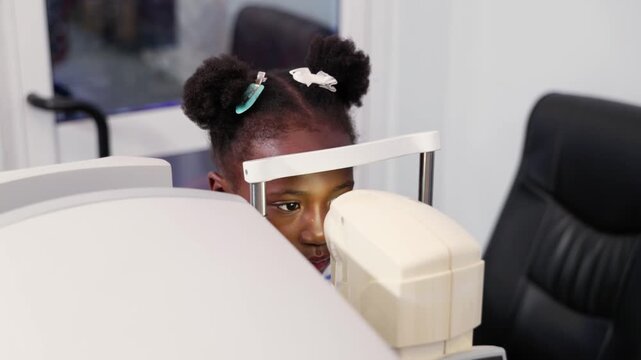 Young African girl child having her vision checked by non-contact tonometer (NCT) in a clinic