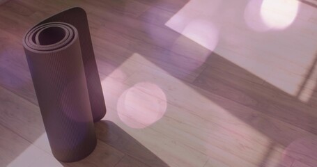 Standing rolled dark yoga mat casting long shadow on plank floor, window shadows, bokeh, copy space
