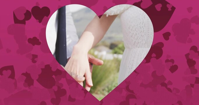 Holding couple wearing white lace dress and dark jacket embracing in outdoor hills, heart frame