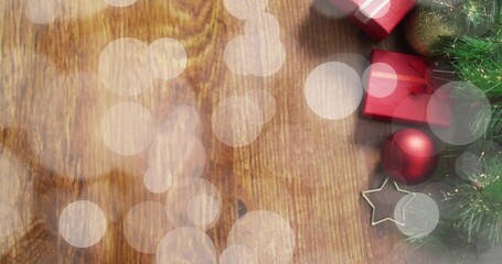 Displaying holiday decor on wooden table with bokeh overlays red gifts baubles star fir, copy space