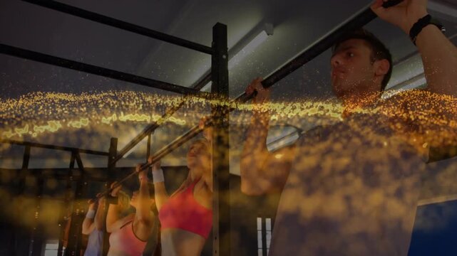 Group gripping bars, starting pull-ups while golden overlay sweeping over group for fitness class