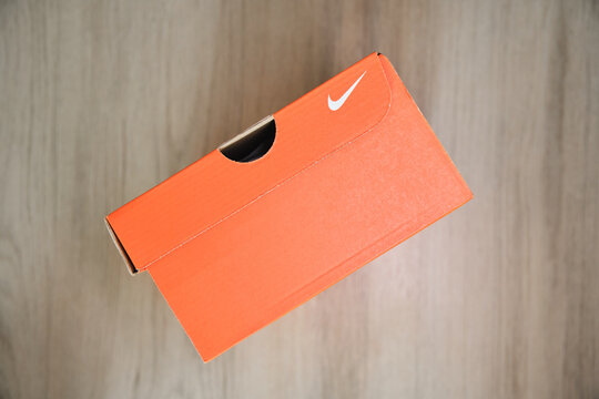 Nike shoebox in orange packaging with white swoosh logo on a wooden floor
