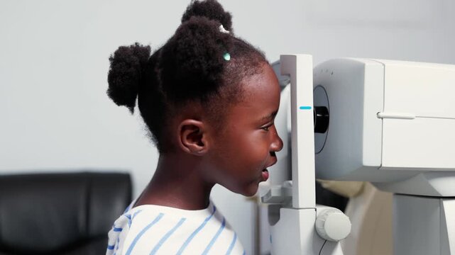 Young African girl child receiving an ocular examination using autorefractor machine in a clinic