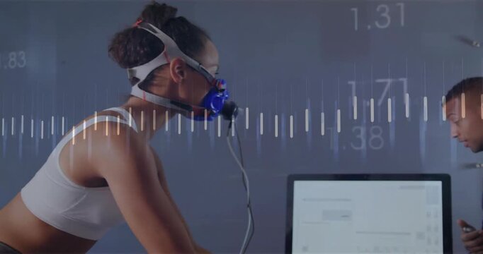 Rider pedaling mask in sports lab driving wave and orange line trainer pointing monitor tuning data