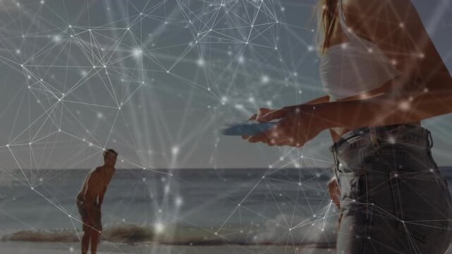Woman shifting stance and throwing blue disc to partner on beach, tech overlay tracking arc