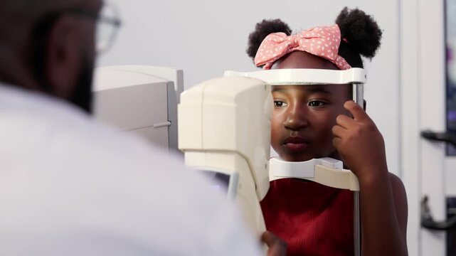 Young African girl child receiving an eye exam from an ophthalmologist using a non-contact tonometer (NCT)