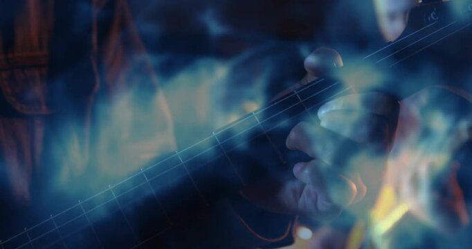 Playing musician fretting and sliding on electric guitar neck at studio, blue smoke, dark jacket