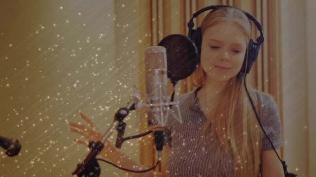 Singer phones cueing, singing into pop mic tracking vocals in studio, sparkly overlay around singer