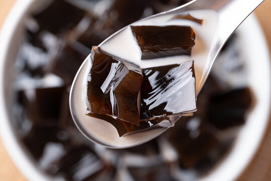 Black grass jelly in fresh milk scooping by spoon, a refreshing Thai dessert in summer season, Top view