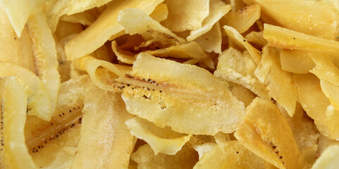 Close up detail of the texture of crispy, golden yellow fried banana chips © Hendri