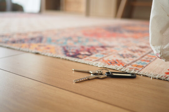 Keys on the floor near a colorful rug in a room. lost key concept 