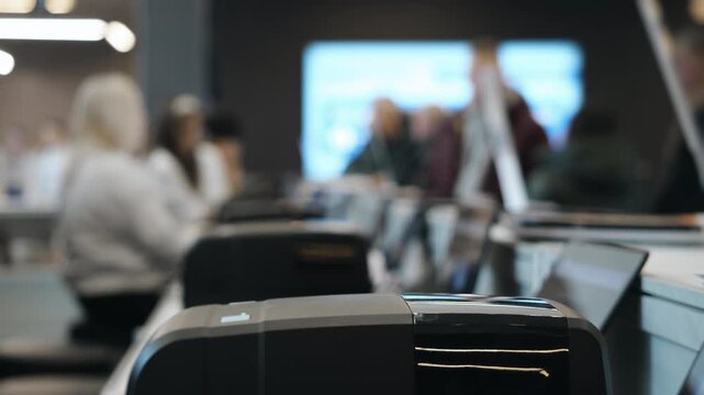 Registration desk at business conference with badge printer and attendees in background. Event check in process during corporate seminar or convention.