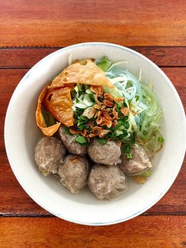 Indonesian Bakso Meatball Noodle Soup in White Bowl on Wooden Table