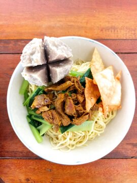 Indonesian Bakso Meatball Noodle Soup in White Bowl on Wooden Table