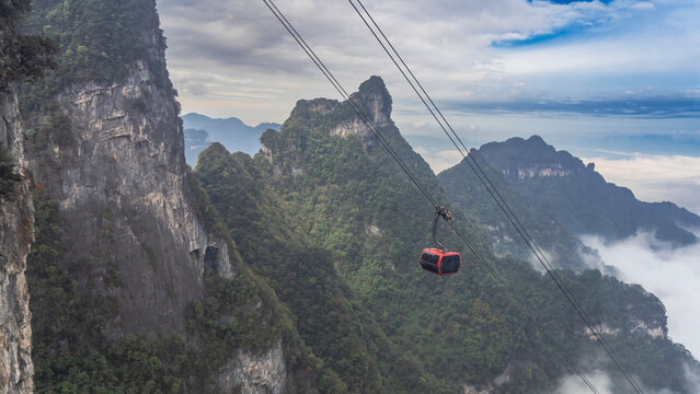 High-altitude cable car. A funicular cabin over a precipice. Picturesque mountains, blue sky, clouds. Forest on the slopes. China. Zhangjiajie. Tianmen Mountain