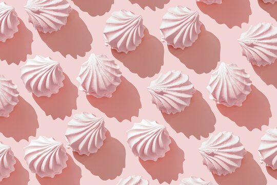 Pink zephyr, marshmallow on Pastel Pink Background, Top view repeated pattern of swirled meringue cookies with sun shadows, minimal flat lay pfoto, sweet dessert, monochrome, childhood nostalgia
