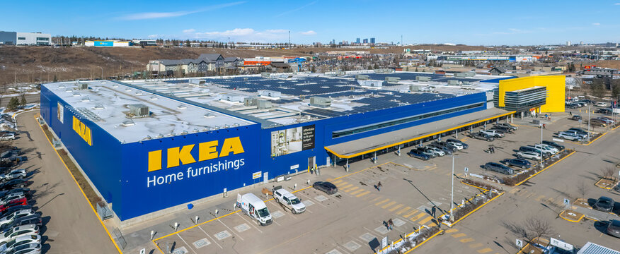 Calgary, Alberta, Canada. March 11, 2026. Wide aerial view of an IKEA home furnishings store with solar panels on the roof under a clear blue sky. High-angle exterior shot 